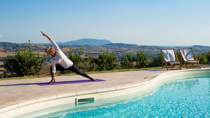 Eine Frau übt Yoga am Pool