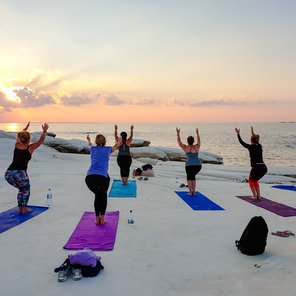 Yoga-übende Frauen auf Ihren Yoga Matten am Meer bei Sonnenuntergang