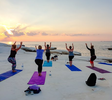 Yoga-übende Frauen auf Ihren Yoga Matten am Meer bei Sonnenuntergang