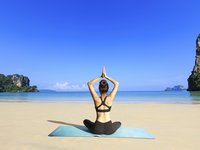 Eine Frau übt Yoga am Meer 