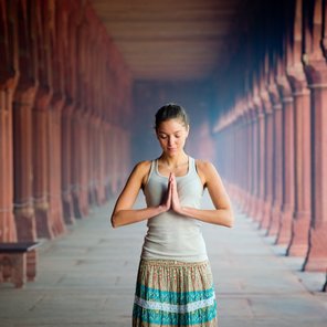 Eine junge Frau steht in einem Tempel die Hände im anjali mudra