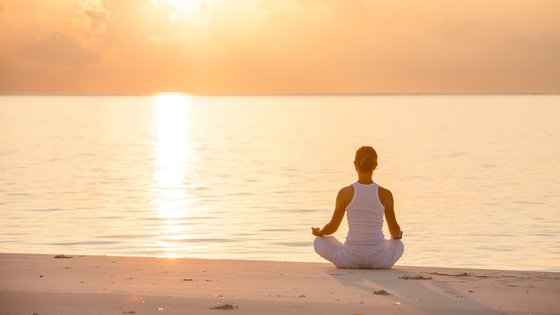 Eine Frau übt Yoga an der Küste