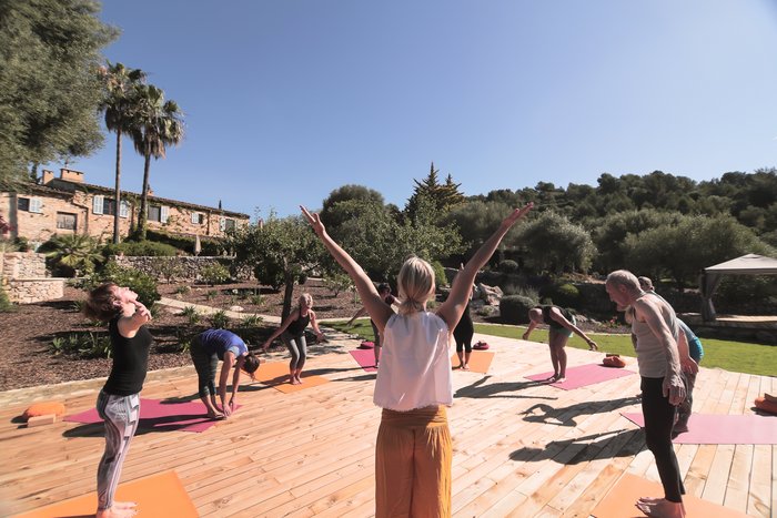 Eine Gruppe übt Yoga auf einer Terasse im Garten