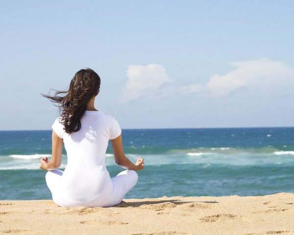 Eine Frau macht eine Yoga-Meditation am Strand