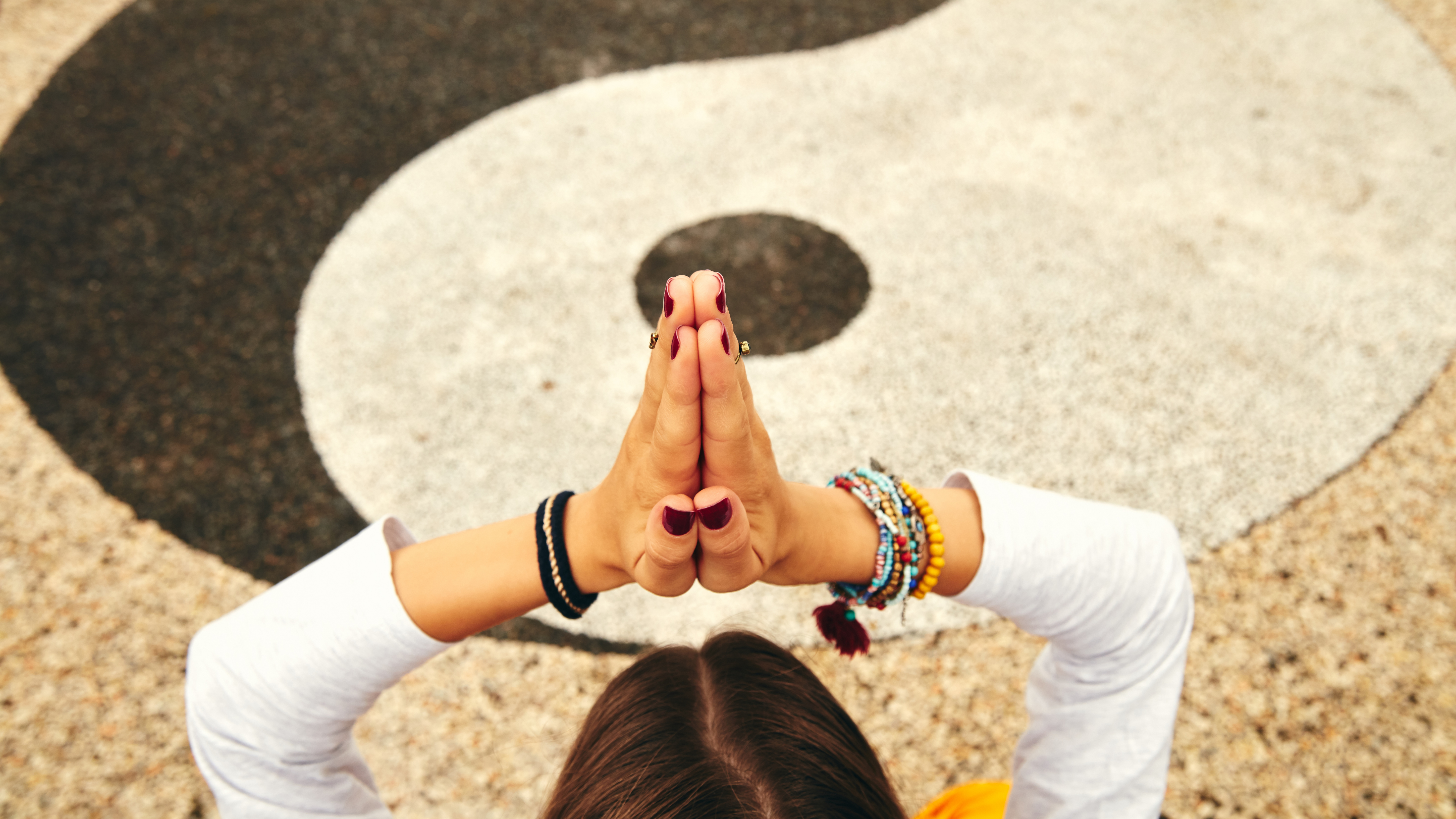 Eine junge Frau übt Yoga in einem tropischen Garten vor einem Yin-Yang Zeichen