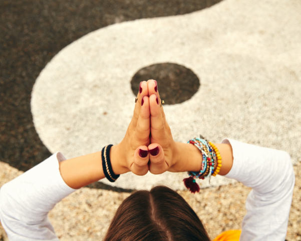 Eine junge Frau übt Yoga in einem tropischen Garten vor einem Yin-Yang Zeichen