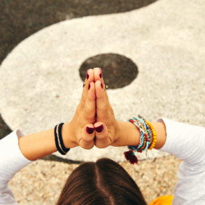 Eine junge Frau übt Yoga in einem tropischen Garten vor einem Yin-Yang Zeichen