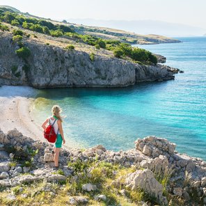 Eine Frau steht auf Klippen und blickt in eine Bucht 