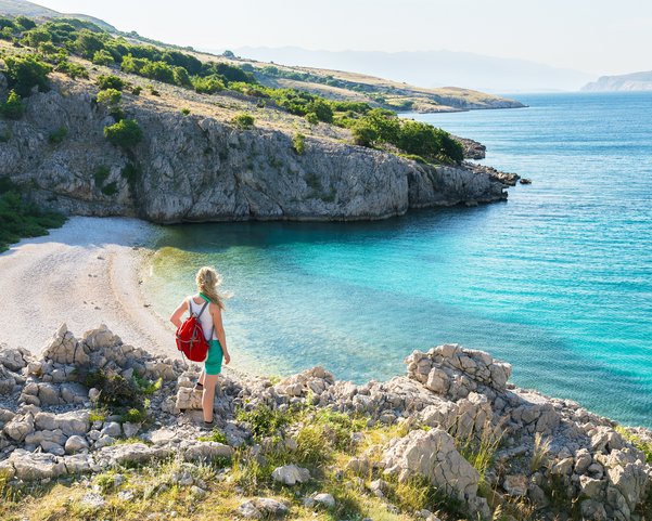 Eine Frau steht auf Klippen und blickt in eine Bucht