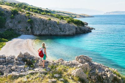 Eine Frau steht auf Klippen und blickt in eine Bucht 