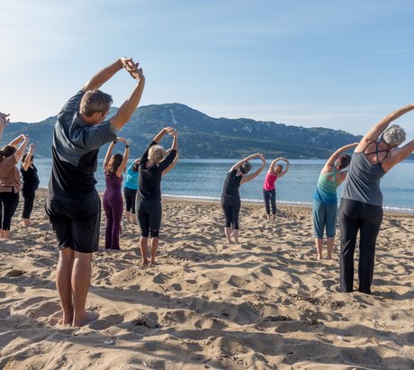 Eine Yoga-Gruppe dehnt sich am Strand