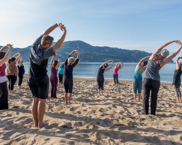 Eine Yoga-Gruppe dehnt sich am Strand