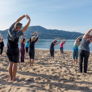 Eine Yoga-Gruppe dehnt sich am Strand