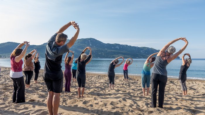 Eine Yoga-Gruppe dehnt sich am Strand