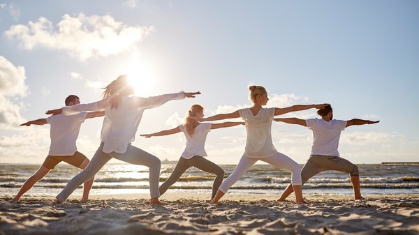 Yogagruppe am Strand bei Sonnenuntergang