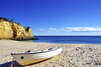 Ein kleines Fischerboot am Strand an der Algarve, Portugal