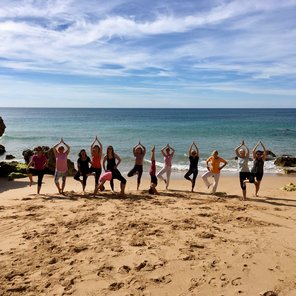 Eine große Gruppe an Frauen in Yoga-Posen am Strand