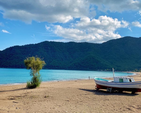 Ein schmales Fischerboot am Strand einer Bucht