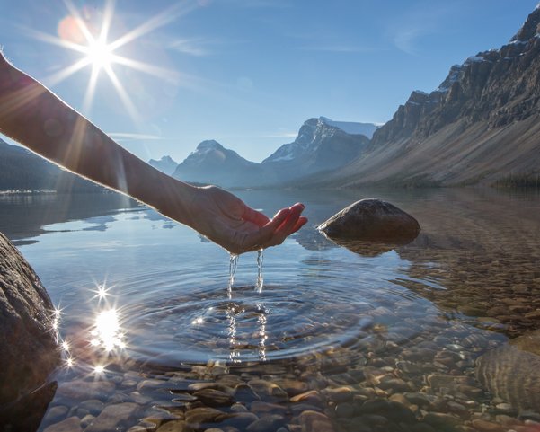 Eine Hand fischt frisches Wasser aus einer Quelle 