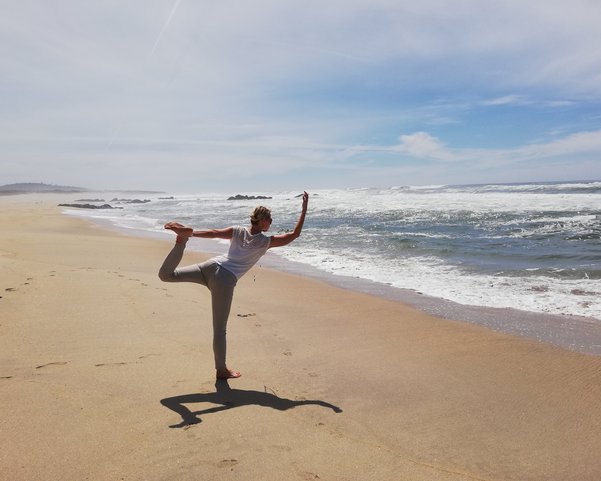 Eine Frau in der Dancer Pose am Strand