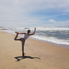 Eine Frau in der Dancer Pose am Strand