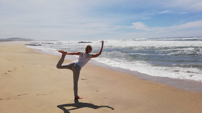 Eine Frau in der Dancer Pose am Strand