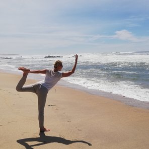 Eine Frau in der Dancer Pose am Strand
