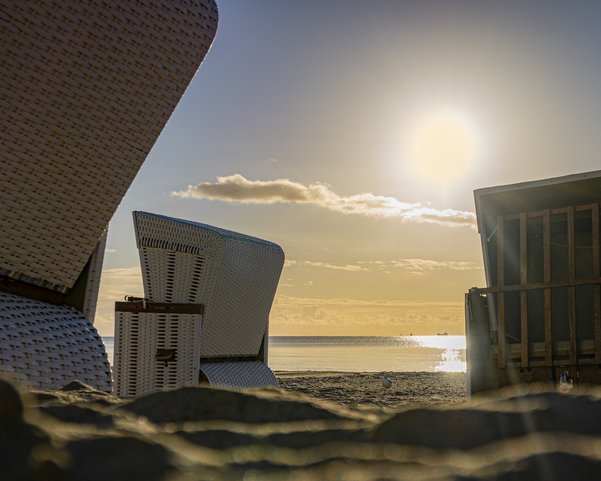 Drei Strandkörbe am Strand bei Sonnenaufgang