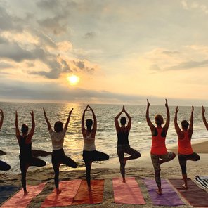 Frauen nebeneinander in der Baum Pose am Strand