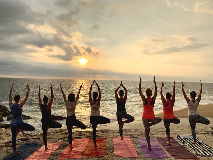 Frauen nebeneinander in der Baum Pose am Strand