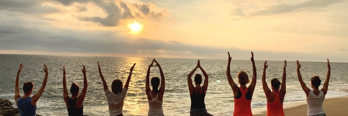 Frauen nebeneinander in der Baum Pose am Strand
