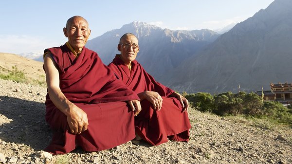 Zwei Mönche sitzen auf einem Berghang im Schneidersitz