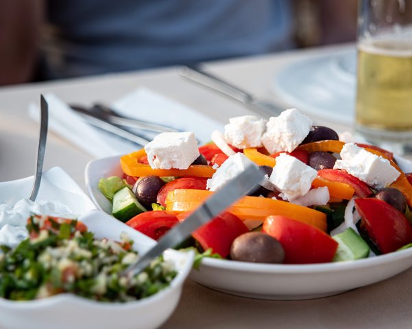 Ein gedeckter Tisch mit einer Schüssel Salat und zwei kleinen Beilagen dazu