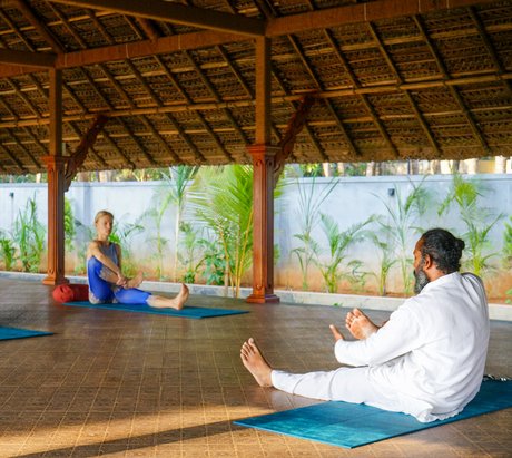 Ein Yogalehrer weist eine Schülerin in eine Position ein