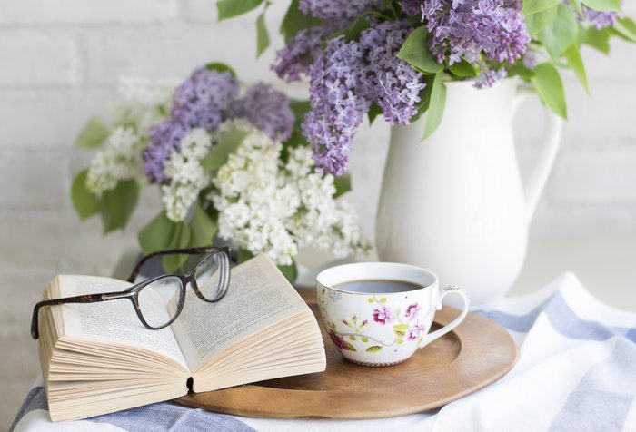 Ein Tablet mit einer Tasse Kaffee und einem Buch mit einer Brille drauf