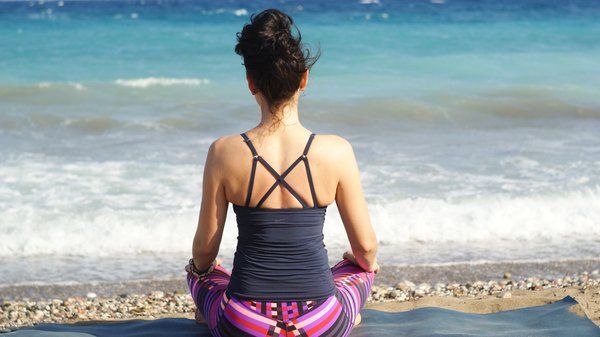 Eine junge Frau übt Yoga an einem Strandufer