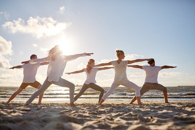 Üben Sie Yoga gemeinsam am Strand mit Gleichgesinnten