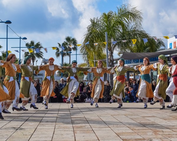 Frauen in Kleidern tanzen Hand in Hand in einem Halbkreis 