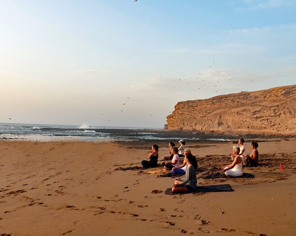 Yogis sitzen im Schneidersitz am Meer