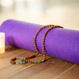 Eine lilane Yogamatte zusammengerollt auf dem Boden