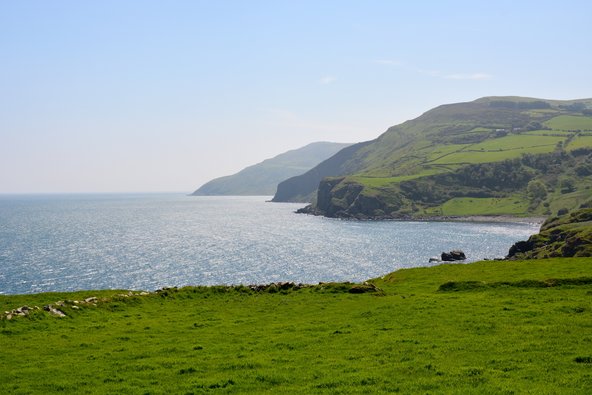 Eine Küste aus grüner Wiese und Bergen am Meer