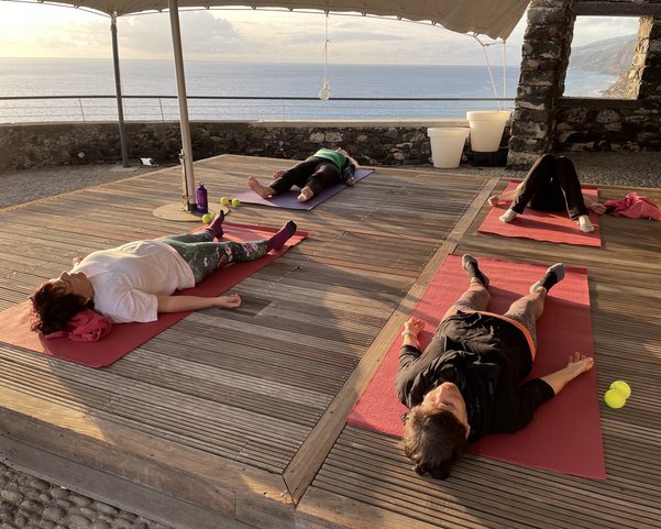 Vier Frauen im Shavasana auf einer Terasse