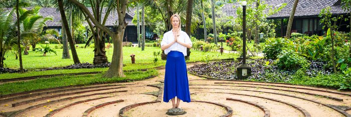 Eine Frau steht in einem Garten die Hände in anjali mudra