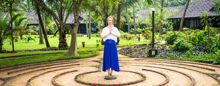 Eine Frau steht in einem Garten die Hände in anjali mudra