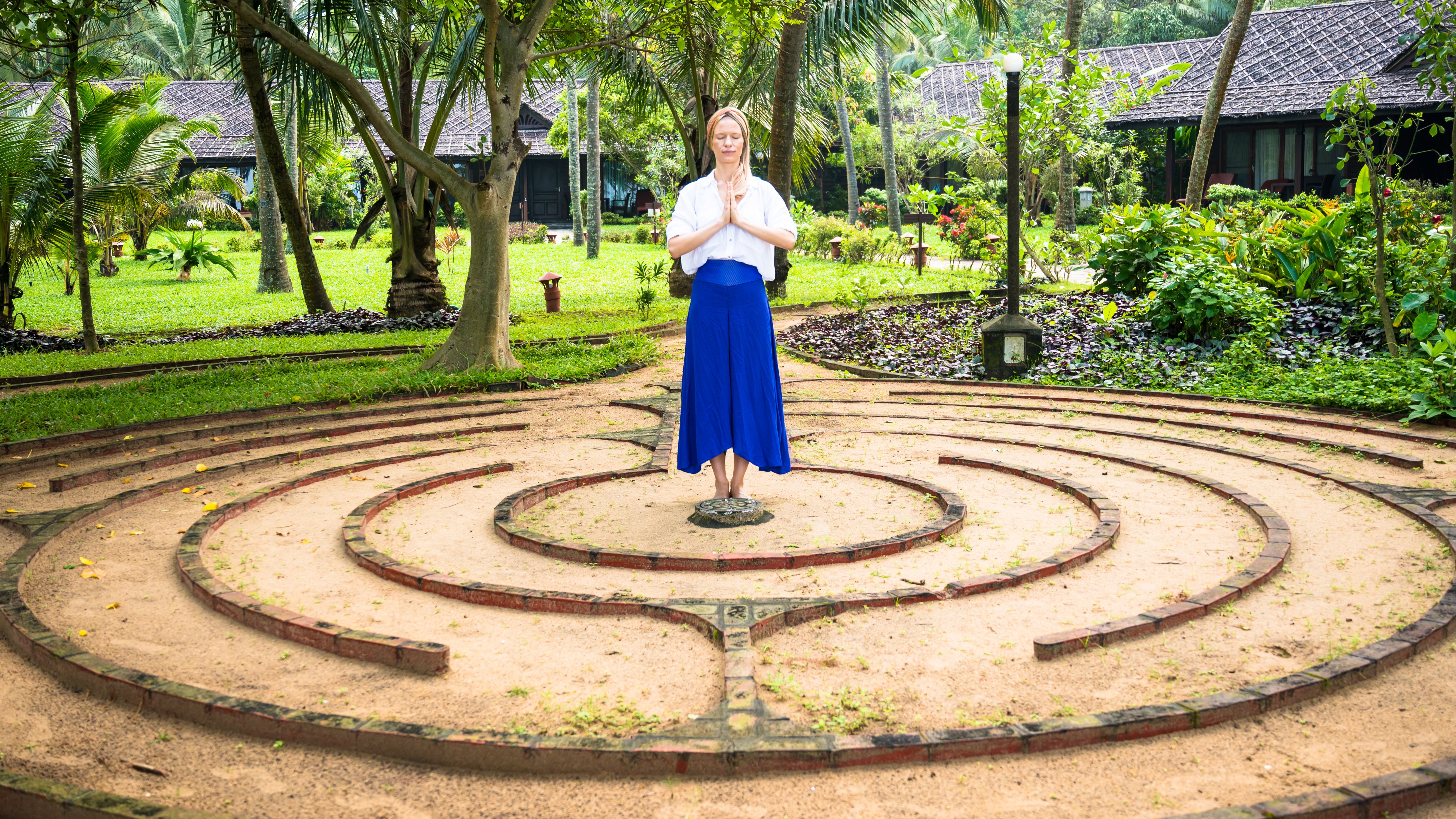 Eine Frau steht in einem Garten die Hände in anjali mudra