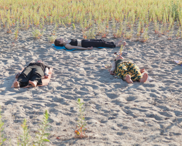 Mehrere Menschen beim Yoga Nidra am Strand