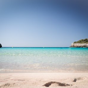 Einen Bucht zwischen zwei Klippen mit türkisblauem Meer und hellem Sand