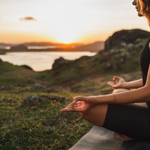 Eine Frau übt in Lotusposition Yoga in der Natur