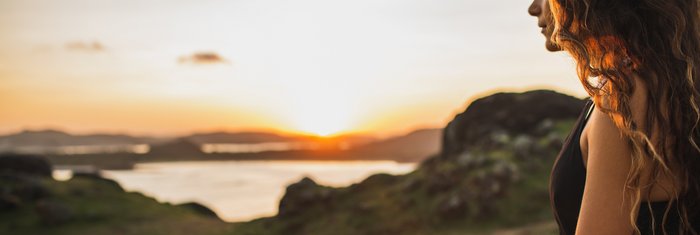 Eine Frau übt in Lotusposition Yoga in der Natur