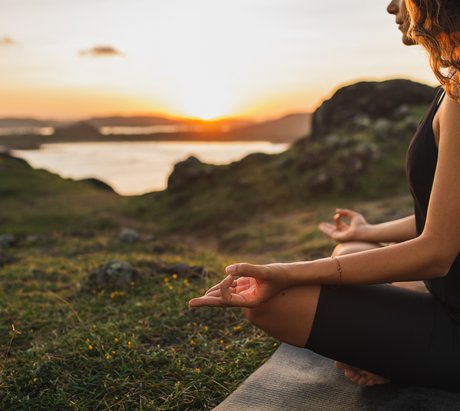 Eine Frau übt in Lotusposition Yoga in der Natur